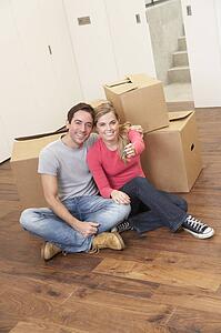 Young couple on moving day sitting with cardboard boxes