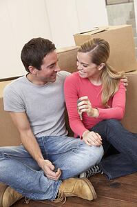Young couple on moving day sitting with cardboard boxes