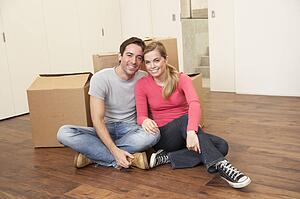 Young couple on moving day sitting with cardboard boxes