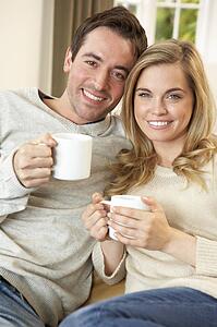 Young couple sitting and relaxing on sofa with cup in hand