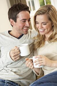 Young couple sitting and relaxing on sofa with cup in hand