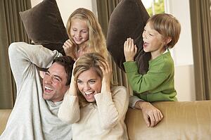 Happy young family having fun with pillows on sofa