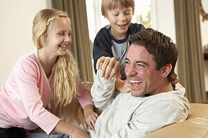 Young father with children having fun on sofa