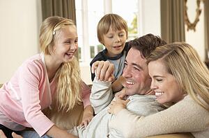Happy young family playing together on sofa
