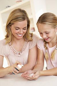 Mother putting sanitizer on young girl's hands