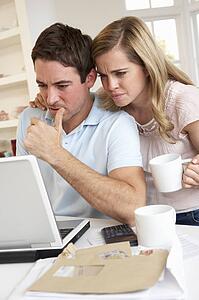 Young couple thinking and looking at a laptop computer