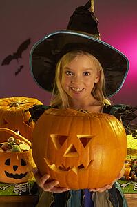 Halloween party with a child holding carved pumpkin