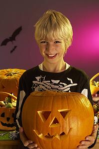 Halloween party with a boy holding carved pumpkin