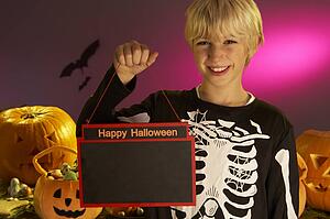 Halloween party with a boy child holding sign