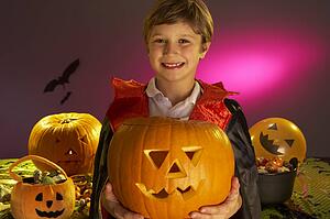 Halloween party with a boy child holding carved pumpkin