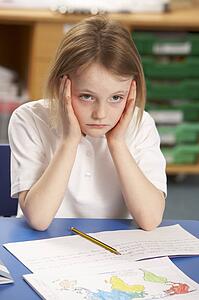 Stressed Schoolgirl Studying In Classroom