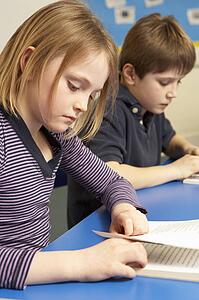 Schoolgirl Reading Book In Classroom