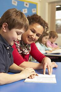 Schoolboy Studying In Classroom With Teacher
