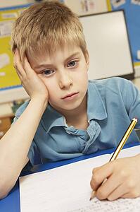 Stressed Schoolboy Studying In Classroom