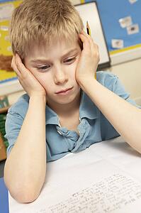 Stressed Schoolboy Studying In Classroom
