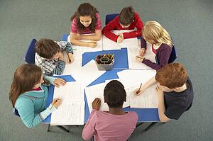 Overhead View Of Schoolchildren Working Together At Desk