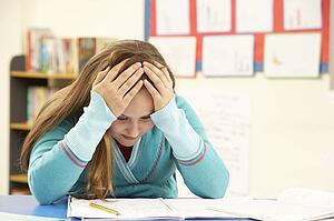 Stressed Schoolgirl Studying In Classroom