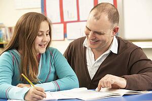 Male Pupil Studying in classroom with teacher