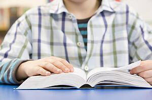 Close Up Of Schoolboy Studying Textbook In Classroom