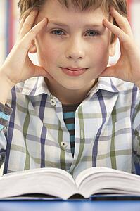 Stressed Schoolboy Studying In Classroom