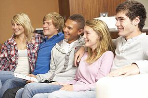 Group Of Teenage Friends Sitting On Sofa At Home Watching TV