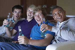 Group Of Teenage Boys Sitting On Sofa At Home Watching Drinking