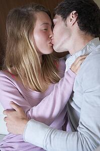 Romantic Teenage Couple Kissing On Sofa At Home Together
