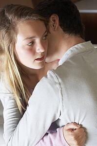 Nervous Looking Teenage Girl Sitting On Sofa At Home With Boyfri