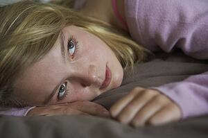 Depressed Teenage Girl Lying In Bedroom