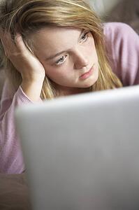 Unhappy Teenage Girl Using Laptop At Home