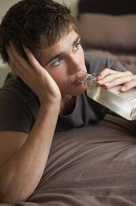Teenage Boy Lying In Bedroom Drinking