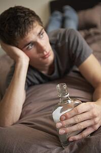 Teenage Boy Lying In Bedroom Drinking