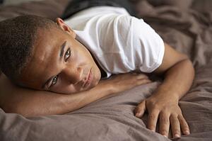 Depressed Teenage Boy Lying In Bedroom