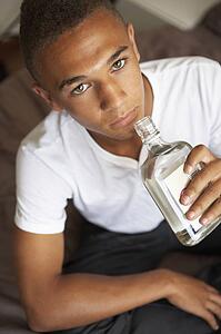 Teenage Boy Lying In Bedroom Drinking