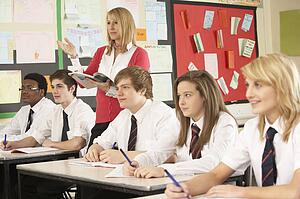 Teenage Students Studying In Classroom With Teacher