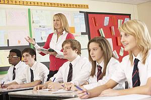 Teenage Students Studying In Classroom With Teacher
