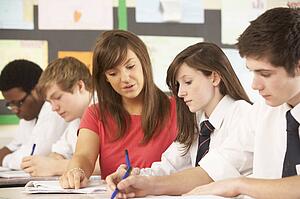 Teenage Students Studying In Classroom With Teacher