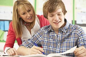 Male Teenage Student Studying In Classroom With Teacher