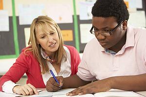 Male Teenage Student Studying In Classroom With Teacher