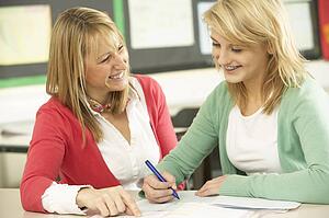 Female Teenage Student Studying In Classroom With Teacher