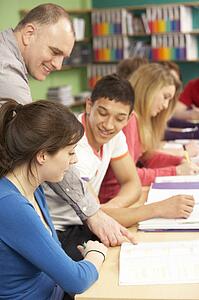 Teenage Students Studying In Classroom With Tutor