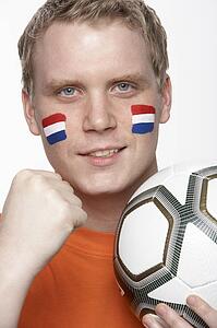 Young Male Football Fan With Dutch Flag Painted On Face