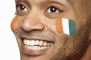 Young Male Sports Fan With Ivory Coast Flag Painted On Face
