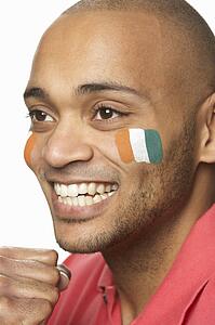 Young Male Sports Fan With Ivory Coast Flag Painted On Face