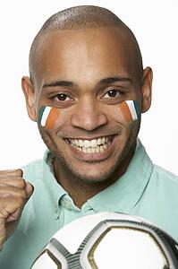 Young Male Football Fan With Ivory Coast Flag Painted On Face