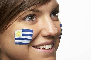 Young Female Sports Fan With Uruguayan Flag Painted On Face