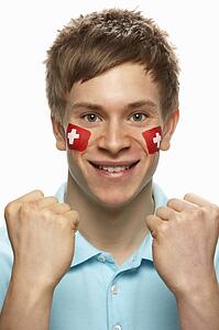 Young Male Sports Fan With Swiss Flag Painted On Face