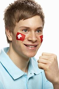 Young Male Sports Fan With Swiss Flag Painted On Face