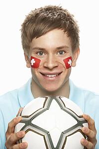 Young Male Football Fan With Swiss Flag Painted On Face