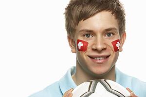 Young Male Football Fan With Swiss Flag Painted On Face